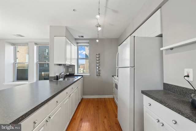 kitchen featuring a sink, visible vents, white cabinetry, range, and freestanding refrigerator