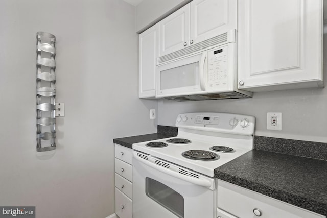 kitchen with dark countertops, white appliances, and white cabinetry