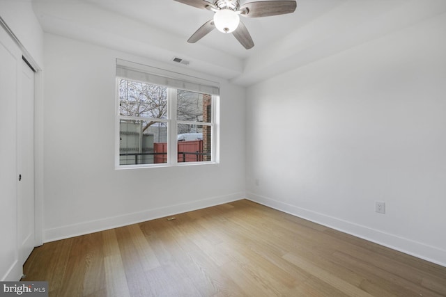 unfurnished bedroom with baseboards, visible vents, ceiling fan, wood finished floors, and a closet