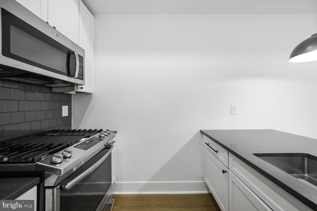 kitchen with stainless steel appliances, tasteful backsplash, dark wood-type flooring, white cabinets, and baseboards