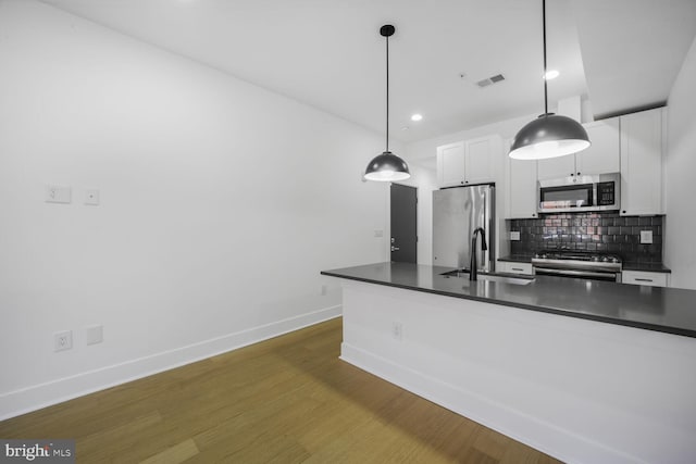 kitchen with stainless steel appliances, dark countertops, tasteful backsplash, visible vents, and a sink