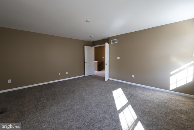 empty room featuring carpet, visible vents, and baseboards