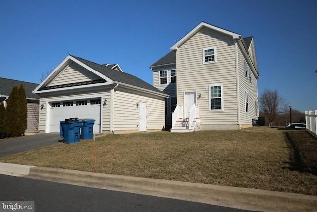 traditional-style house with driveway, entry steps, a garage, an outbuilding, and a front lawn