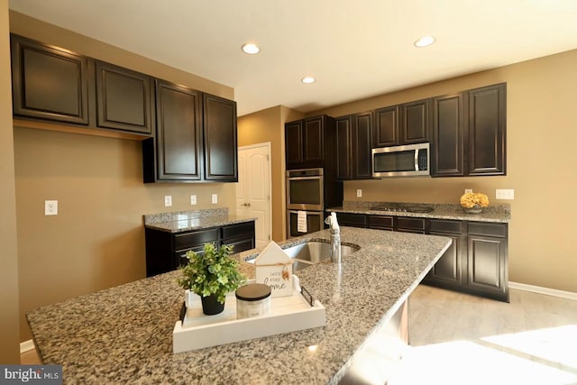 kitchen with recessed lighting, stainless steel appliances, a sink, light wood-style floors, and light stone countertops