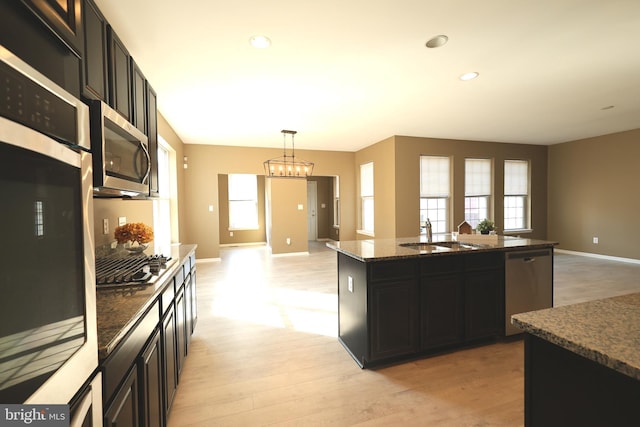 kitchen with stainless steel appliances, open floor plan, a sink, and dark cabinets