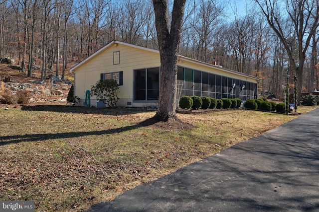 view of side of home featuring a lawn and a sunroom