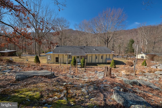 rear view of property featuring a forest view