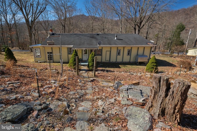 ranch-style house featuring a forest view and a chimney