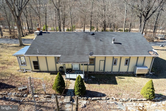 rear view of property with a tiled roof, roof with shingles, and heating fuel