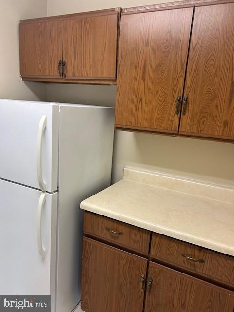 kitchen featuring brown cabinetry, light countertops, and freestanding refrigerator