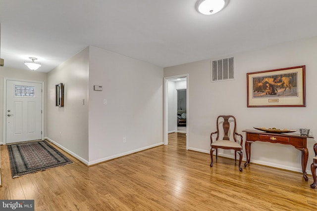 foyer with light wood finished floors, visible vents, and baseboards