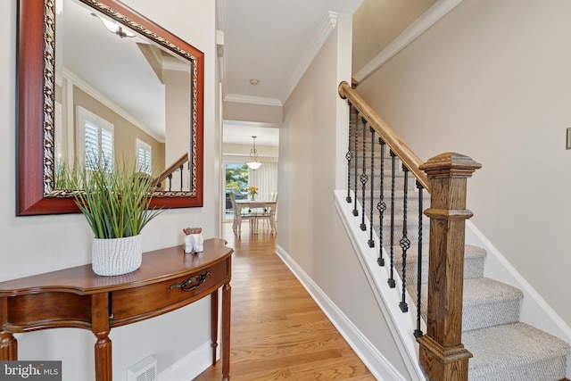 corridor featuring baseboards, visible vents, stairway, crown molding, and light wood-style floors