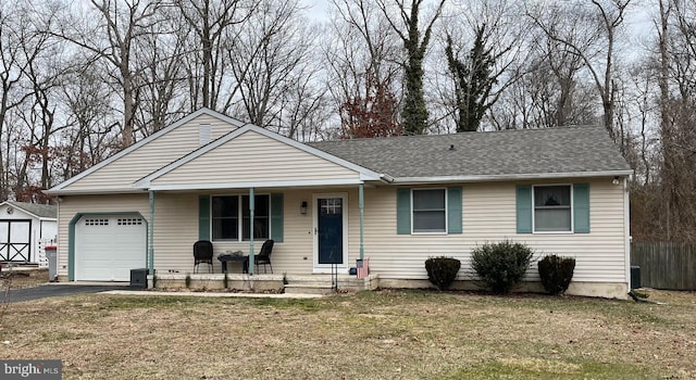 ranch-style home with driveway, roof with shingles, fence, a porch, and a front yard