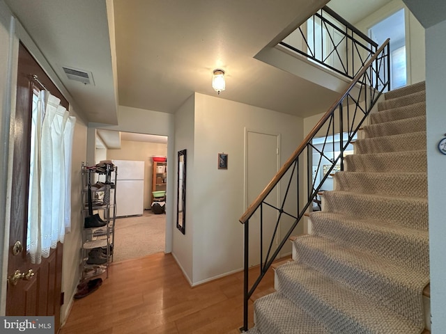 staircase with baseboards, visible vents, and wood finished floors