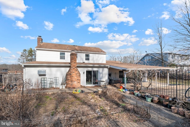 rear view of house with a chimney and fence