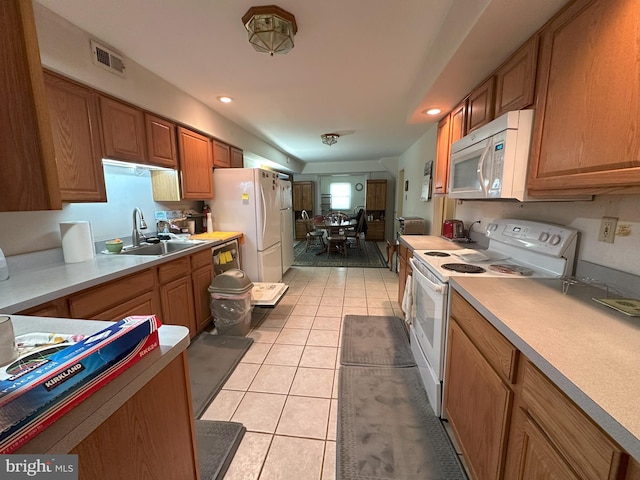 kitchen featuring light tile patterned floors, light countertops, visible vents, a sink, and white appliances