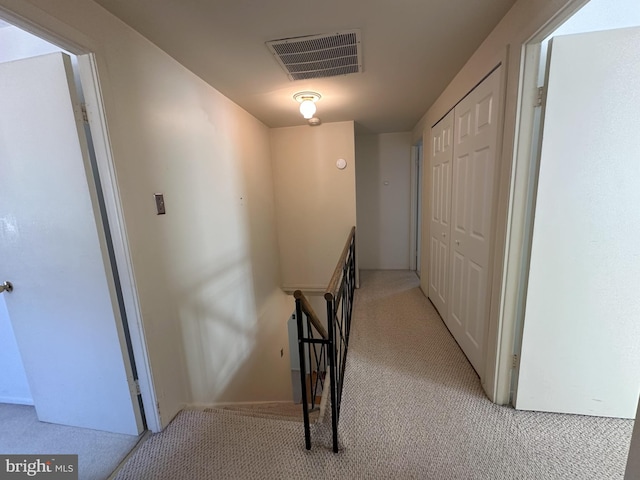 corridor featuring an upstairs landing, visible vents, and light colored carpet