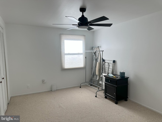 workout area featuring light carpet, baseboards, and a ceiling fan