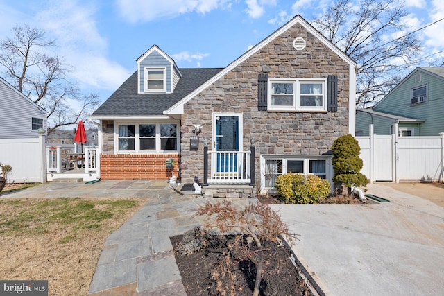 view of front of house with a shingled roof, a gate, and fence