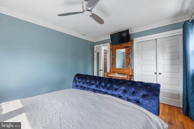 bedroom featuring ornamental molding, a closet, ceiling fan, and wood finished floors