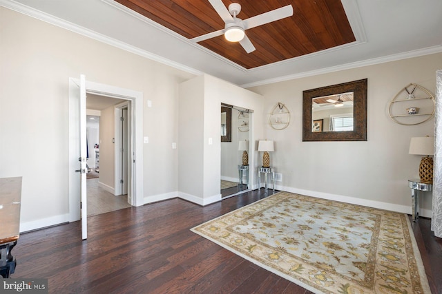 interior space featuring wooden ceiling, ornamental molding, a raised ceiling, and wood finished floors