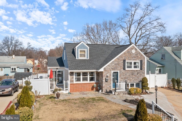 view of front of home with a shingled roof, a gate, fence, and concrete driveway