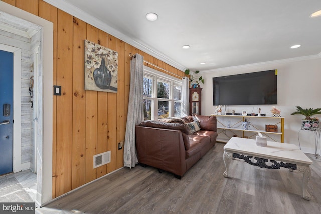 living room with wooden walls, visible vents, wood finished floors, crown molding, and recessed lighting