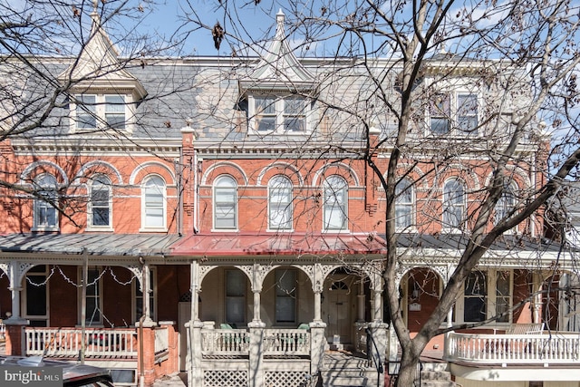 townhome / multi-family property featuring covered porch and brick siding