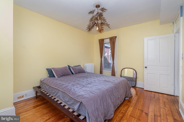 bedroom featuring radiator, light wood finished floors, and baseboards