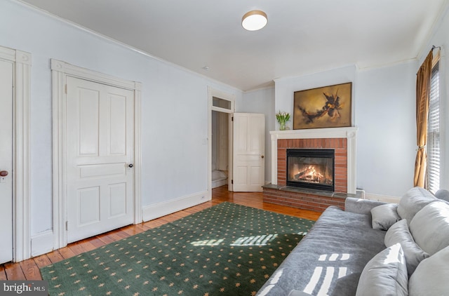 living area with a fireplace, ornamental molding, and wood finished floors