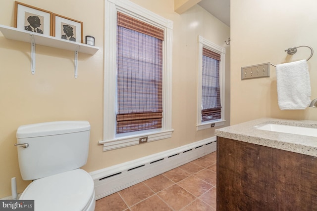 bathroom featuring a baseboard heating unit, tile patterned flooring, vanity, and toilet