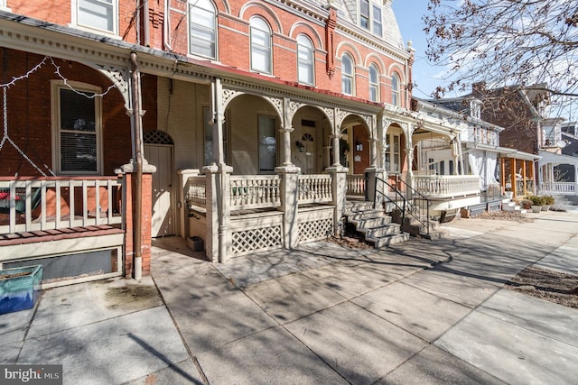 view of front facade featuring a porch, brick siding, and mansard roof