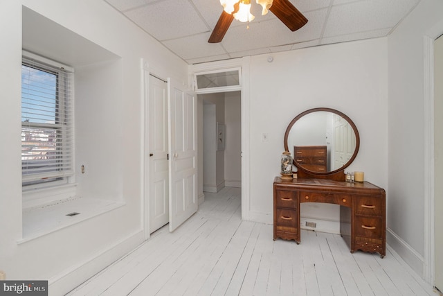 bathroom featuring a paneled ceiling, a ceiling fan, baseboards, and wood finished floors