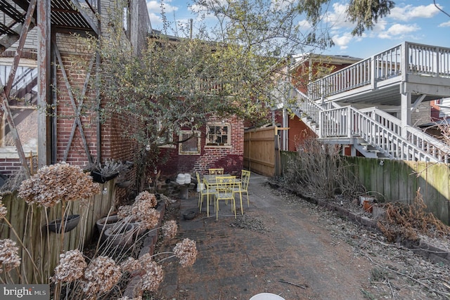 view of patio / terrace featuring fence and stairs