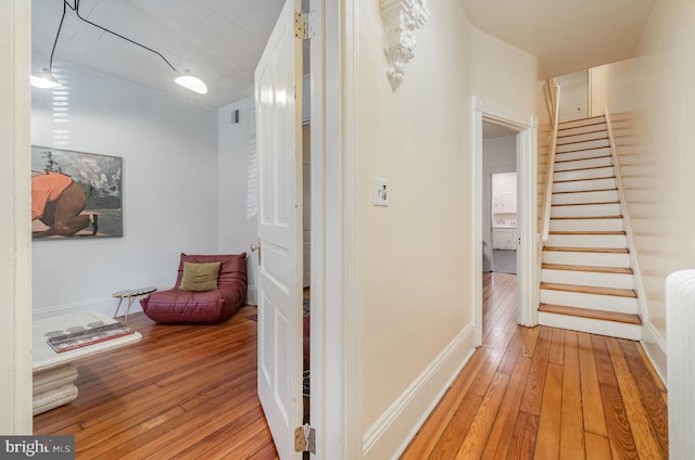 corridor with stairs, baseboards, visible vents, and light wood-style floors