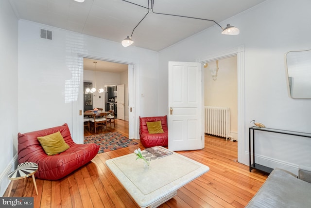 living room with light wood-style floors, radiator, visible vents, and a notable chandelier