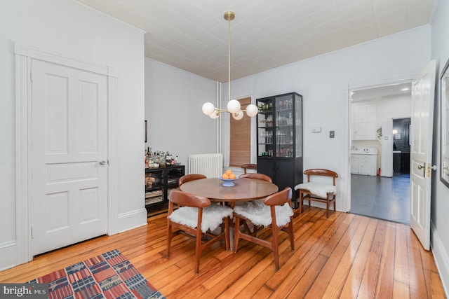 dining space featuring light wood-type flooring, radiator, and an inviting chandelier