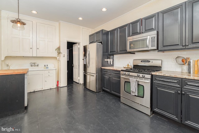 kitchen with recessed lighting, hanging light fixtures, decorative backsplash, appliances with stainless steel finishes, and butcher block countertops