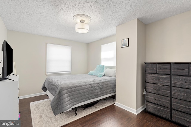 bedroom with baseboards, a textured ceiling, and dark wood-style flooring