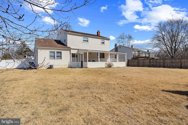 back of property featuring a yard, fence, and a chimney