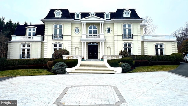 view of front of property featuring stucco siding, mansard roof, and a balcony