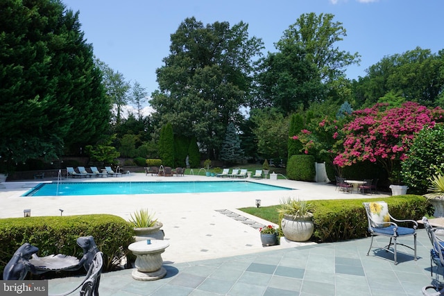 community pool with a patio and fence