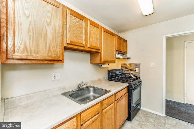 kitchen with under cabinet range hood, a sink, baseboards, light countertops, and black range with gas stovetop