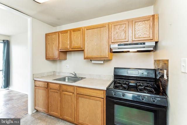 kitchen with light floors, light countertops, black gas range oven, a sink, and under cabinet range hood