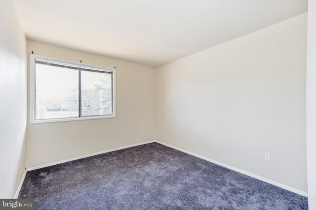 empty room featuring carpet and baseboards