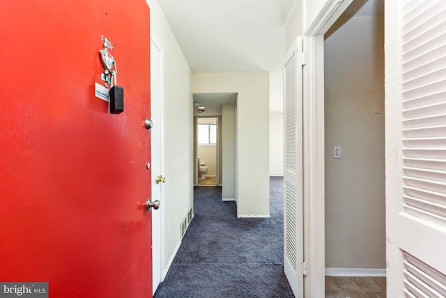 corridor featuring carpet floors, visible vents, and baseboards