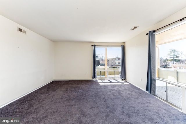 empty room featuring carpet, visible vents, and baseboards