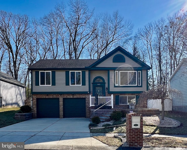 bi-level home with an attached garage, brick siding, and driveway