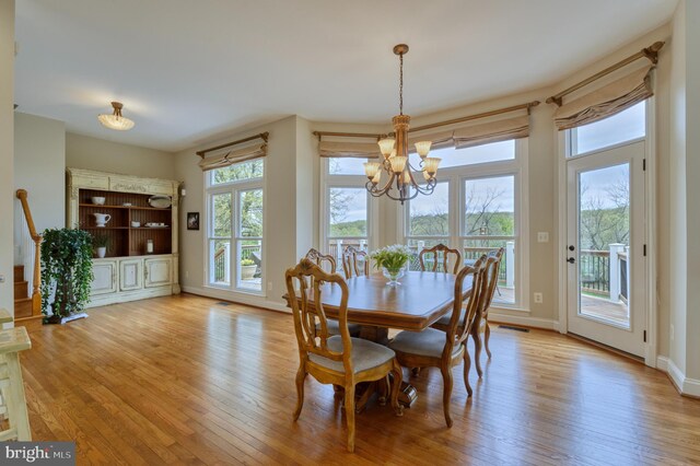 dining area featuring light wood-style flooring, an inviting chandelier, baseboards, and visible vents