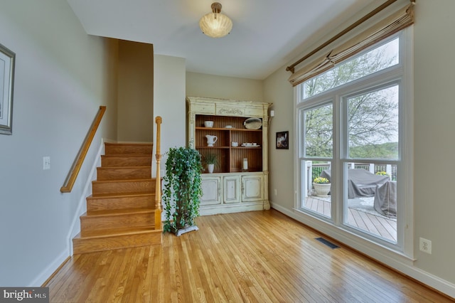 interior space with stairway, visible vents, baseboards, and hardwood / wood-style floors